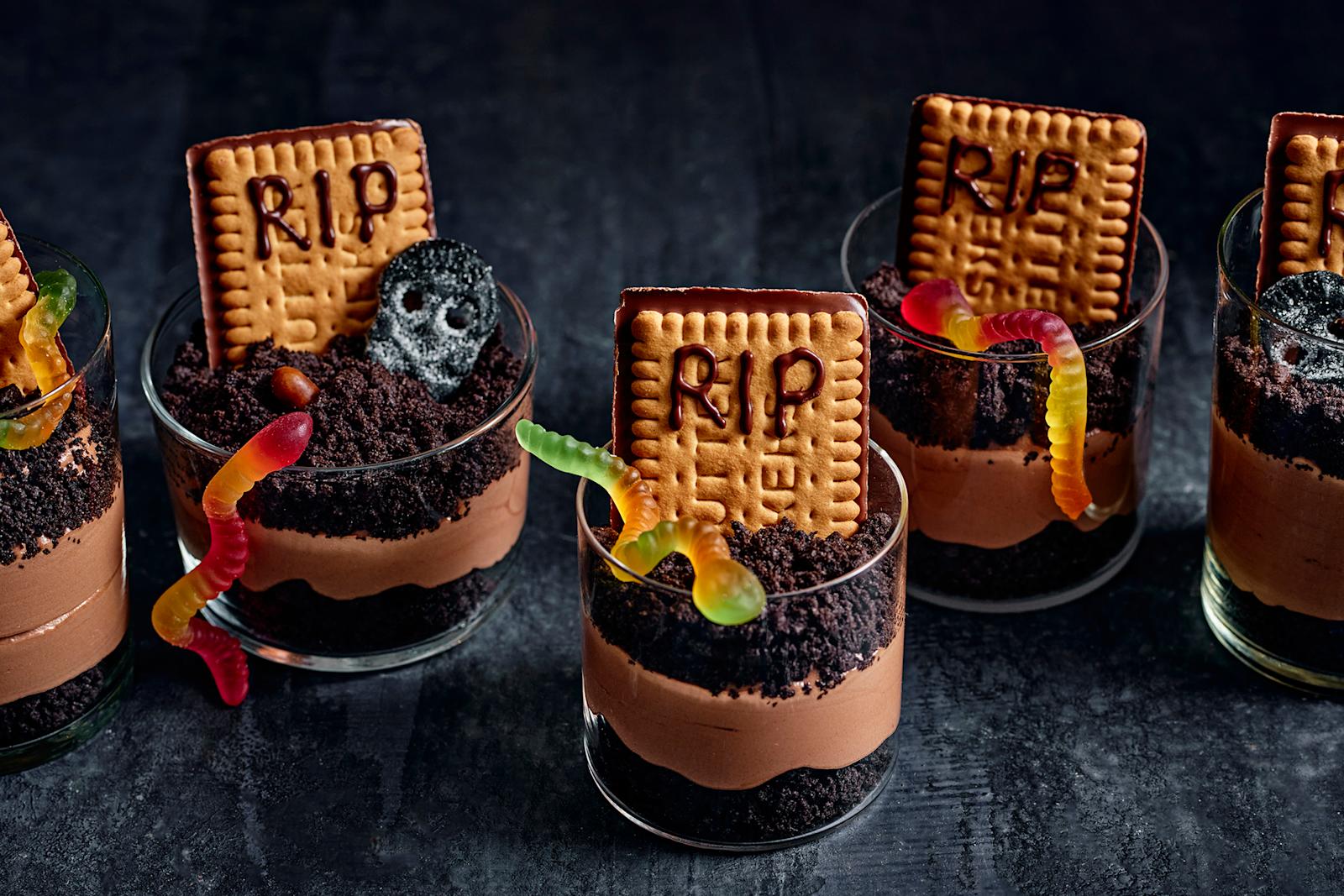 Neljä suklaamousseannosta, jotka on koristeltu suklaakekseillä ja halloween-karkeilla.