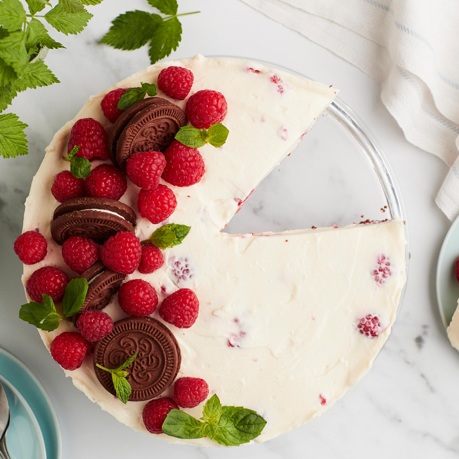 Vadelmajuustokakku, josta leikattu pala lautaselle kakun viereen.