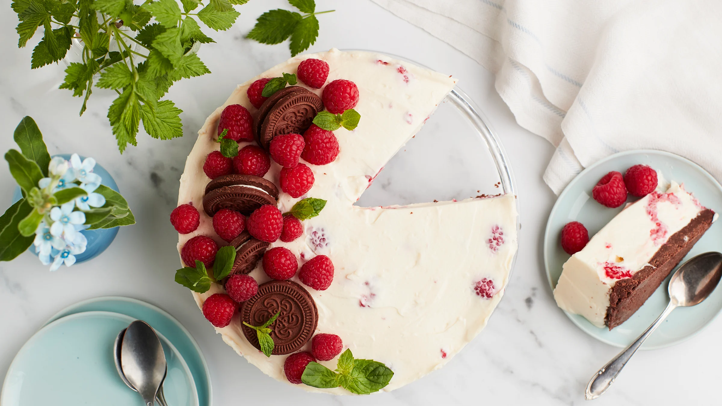 Vadelmajuustokakku, josta leikattu pala lautaselle kakun viereen.