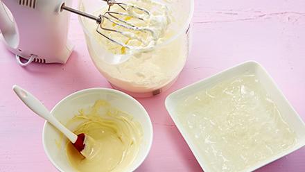 Valmista kakun täyte. Liota liivatelehtiä kylmässä vedessä 10 minuuttia. Sulata valkosuklaa ja anna jäähtyä. Vaahdota kerma.