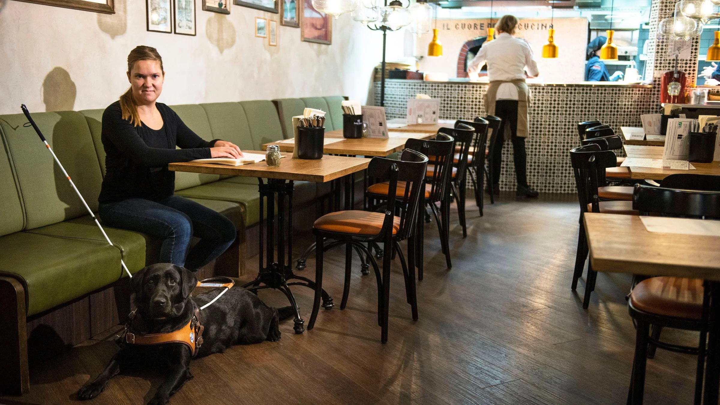 Näkövammainen Susanna Halme istuu Rosson ravintolapöydässä lukemassa ruokalistaa.