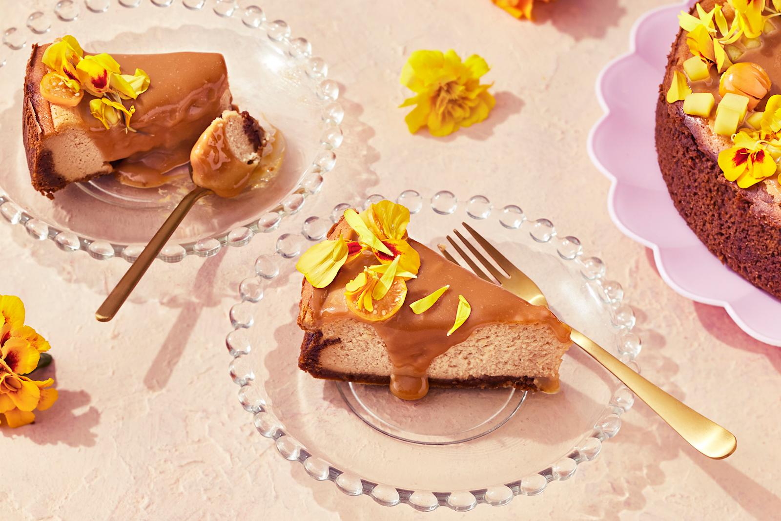 Suolakinuski-juustokakku, josta leikattu kaksi palaa lasisille lautasille. Kakkupalat koristeltu keltaisilla samettikukilla.