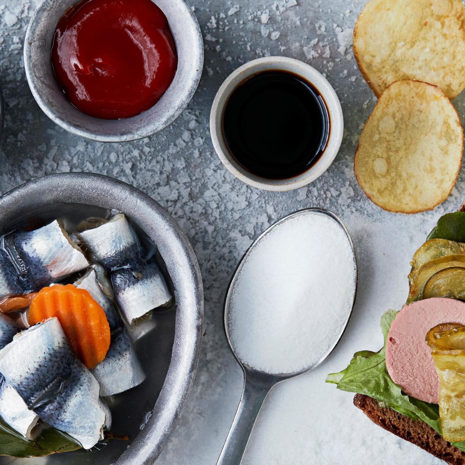 Pöytään on katettu suolakalaa, sipsejä, ketsuppia ja suolaa.