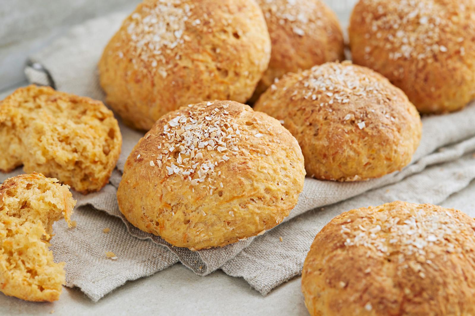 Porkkanasämpylät leivinliinan päällä. Yksi sämpylä halkaistu puoliksi.