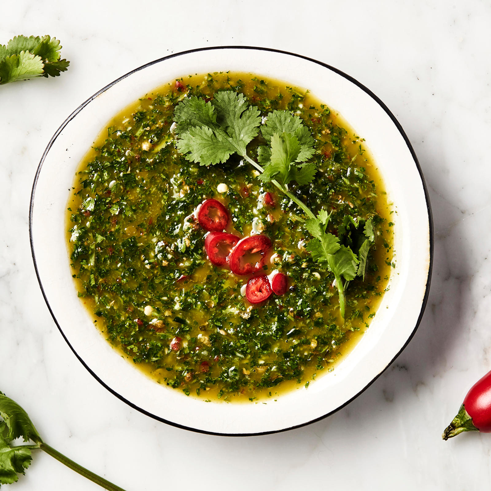 Chimichurri laakeassa kulhossa chiliviipaleilla ja korianterilla koristeltuna.