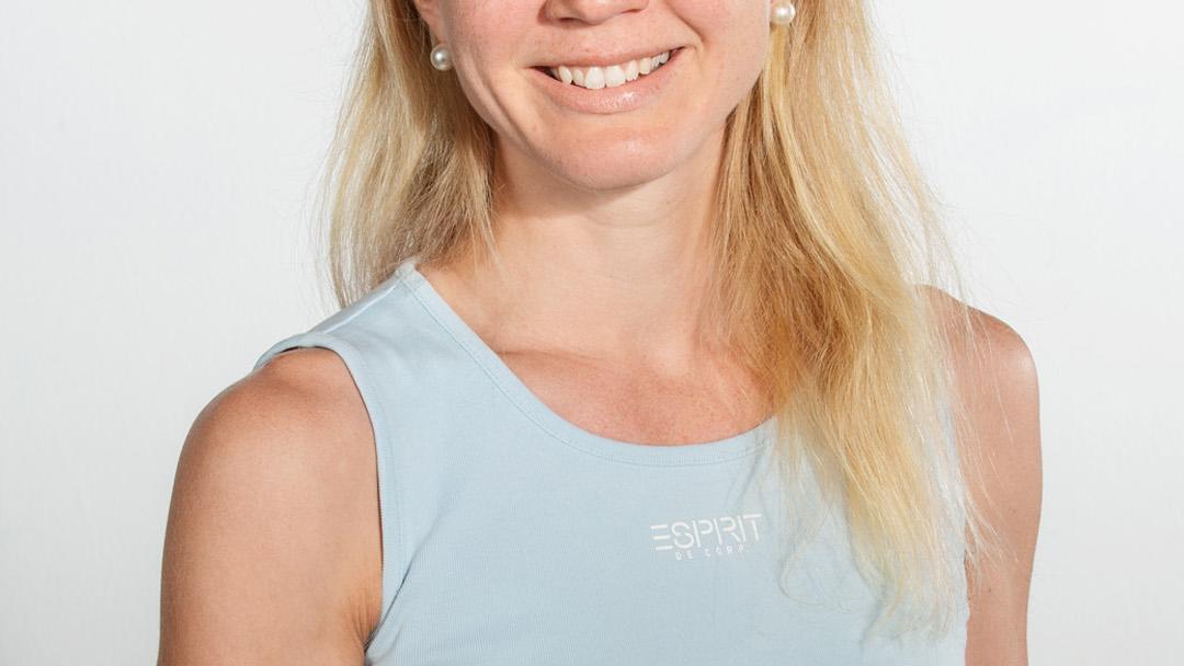 Ravitsemusterapeutti Aino niemi katsoo hymyillen kameraan keittiöpyyhe käsissään.