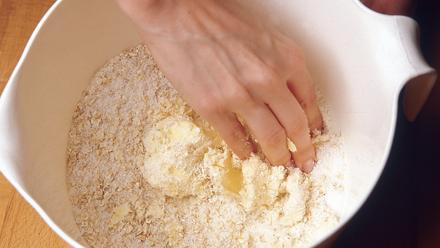 Valmista päällys. Nypi pehmeä rasva, hiutaleet, vehnäjauhot ja sokeri keskenään murumaiseksi seokseksi.