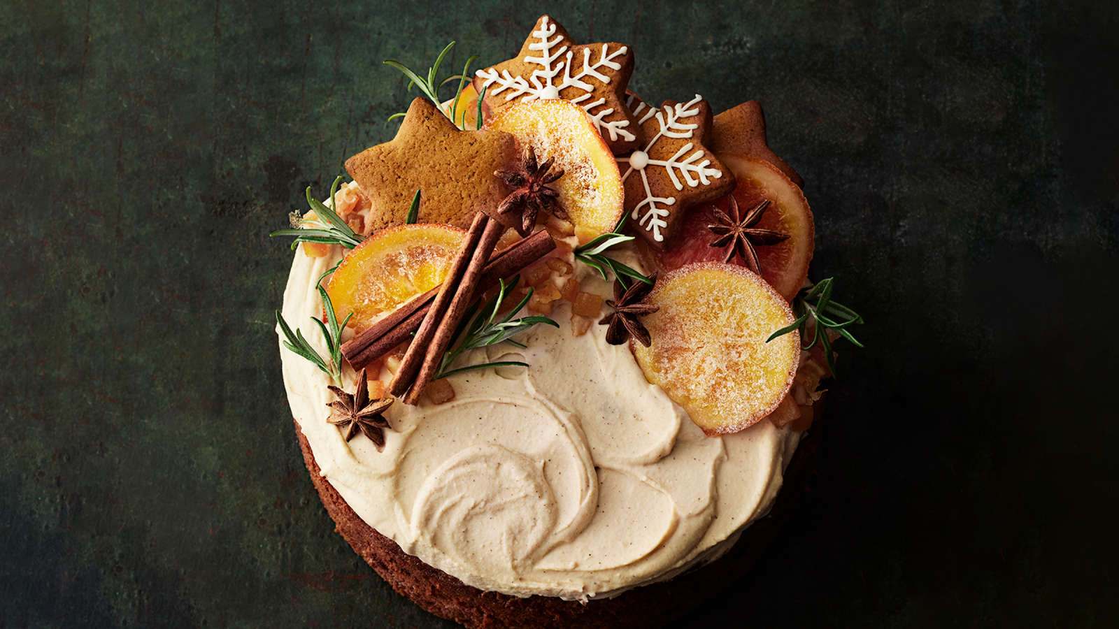 Englantilainen hedelmäkakku tuorejuustovaahdolla kuorrutettuna. Kakku on koristeltu kanelitangoilla, kandeeratuilla appelsiineilla, piparkakuilla, tähtianiksilla ja rosmariinitupsuilla.