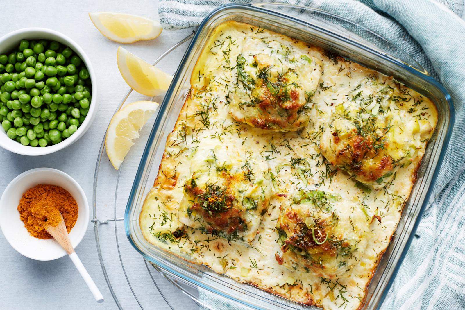 Juustokuorrutteinen seiti uunivuoassa, vieressä kulhossa herneitä