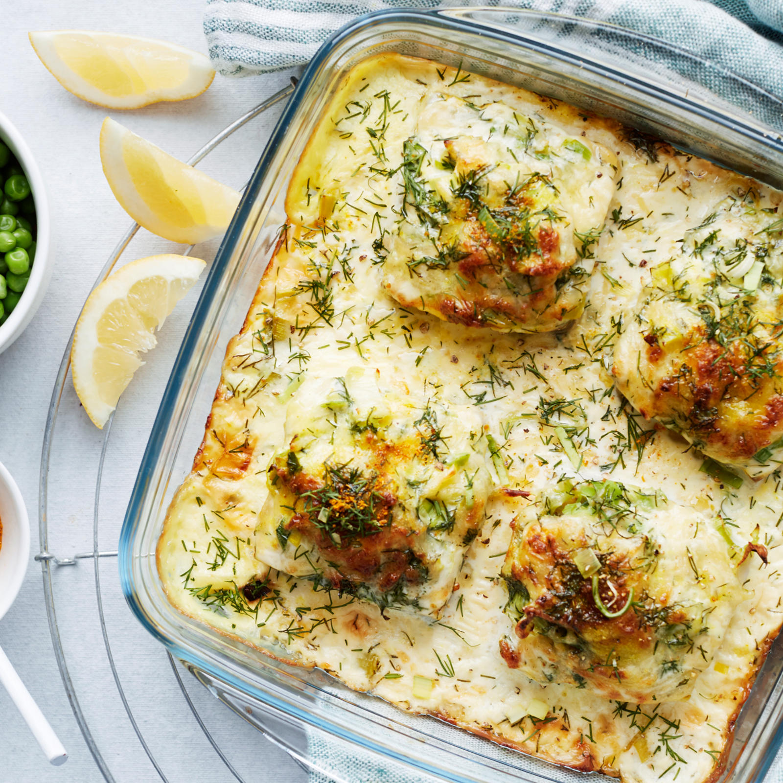 Juustokuorrutteinen seiti uunivuoassa, vieressä kulhossa herneitä