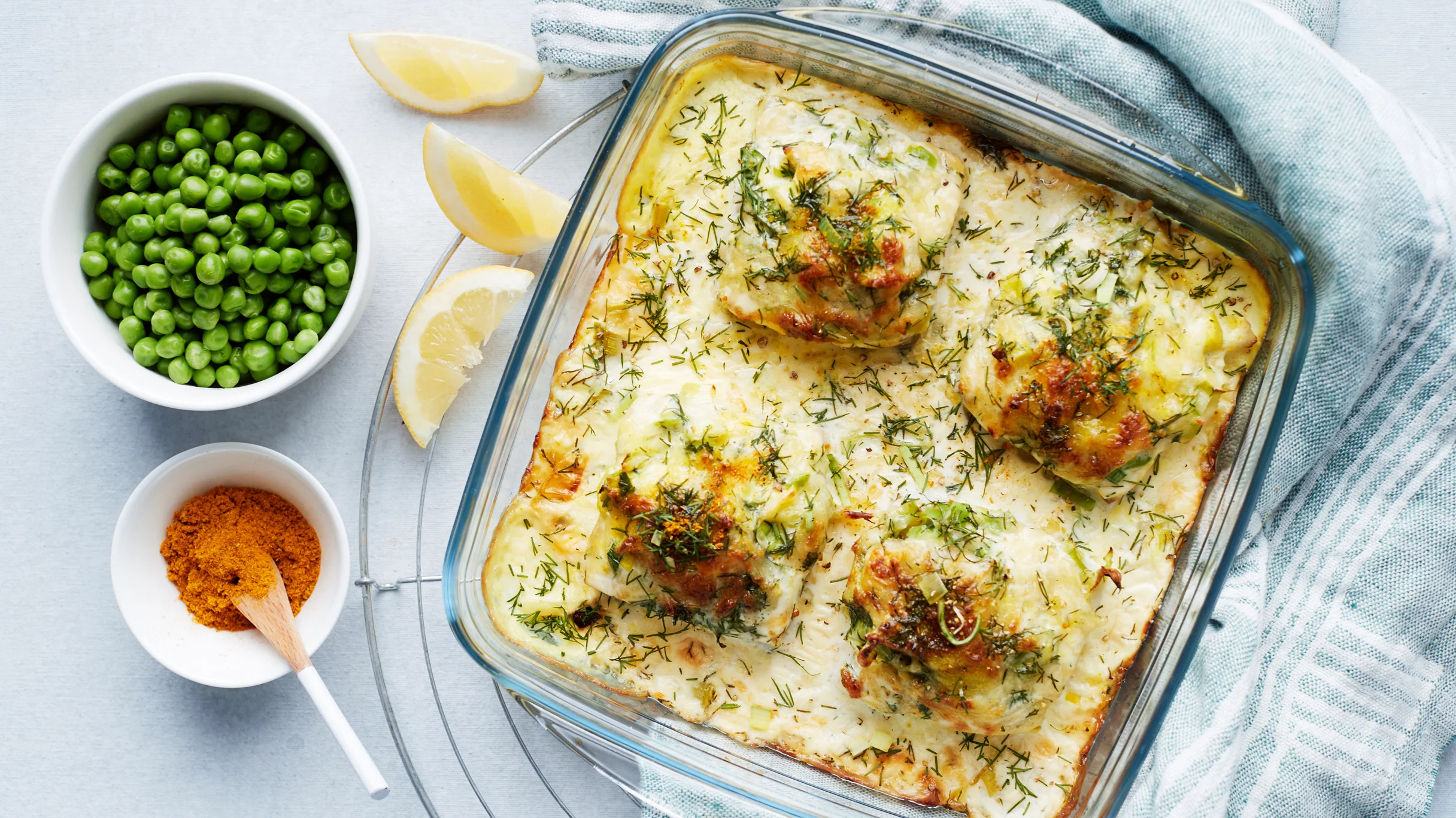 Juustokuorrutteinen seiti uunivuoassa, vieressä kulhossa herneitä