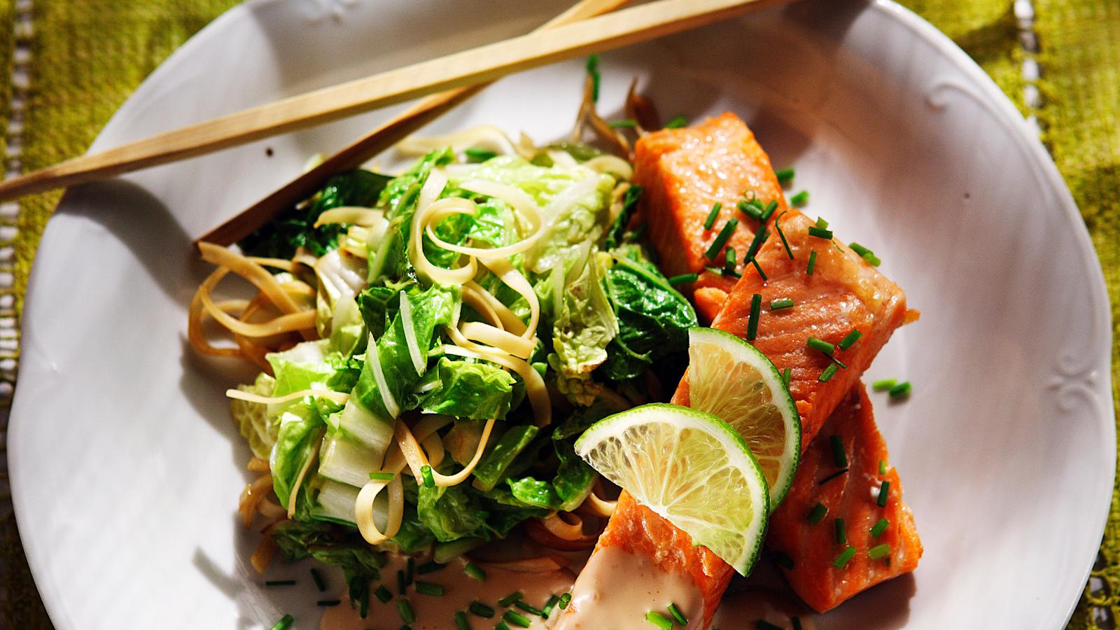 Limeti-kookoslohi sekä nuudeleita ja paistettuja kasviksia lautasella. Lautasen reunalla syömäpuikot