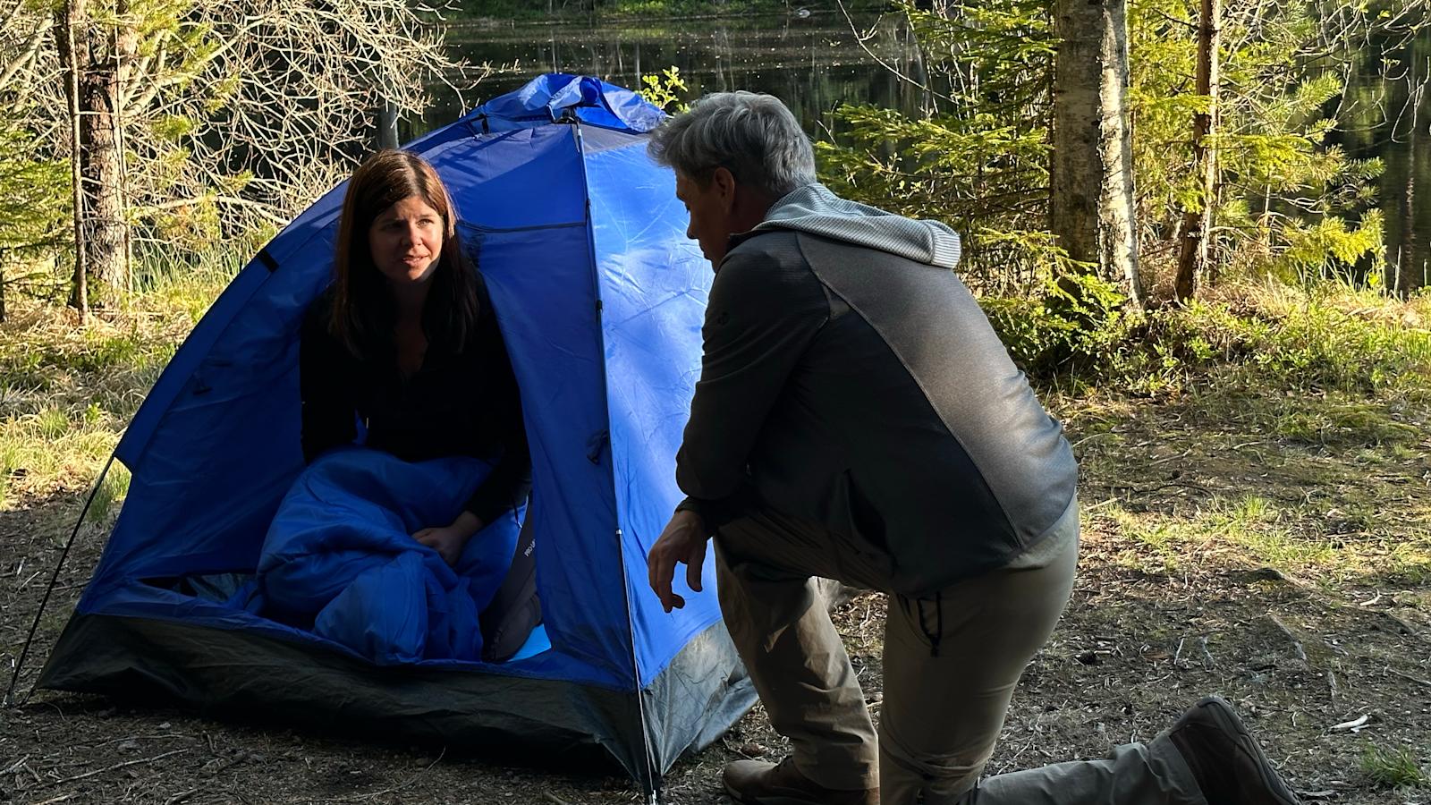 Mirka on pystyttänyt Nuuksioon lammen rannalle teltan ja Jukka ohjeistaa perusasioissa.