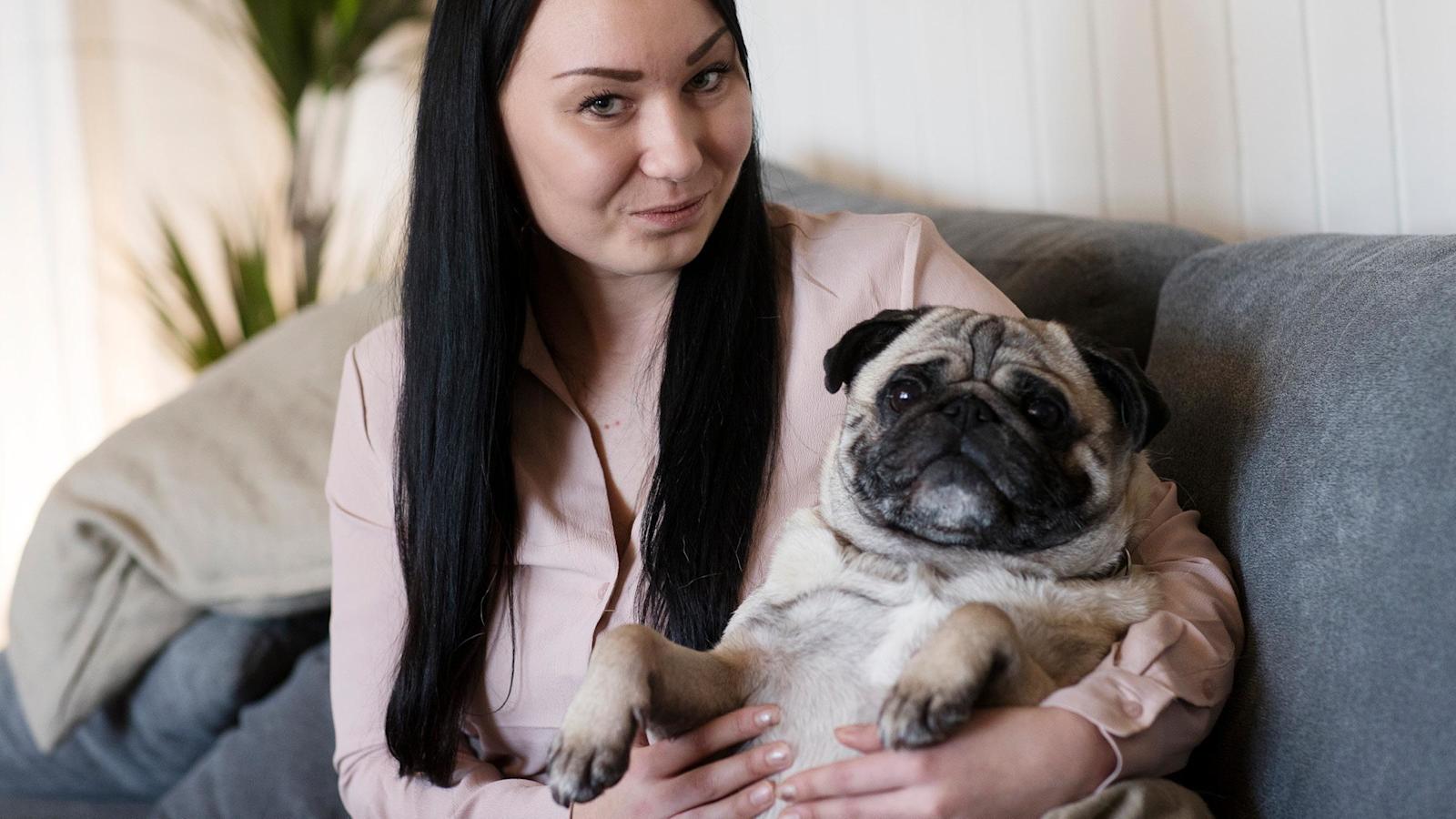 Marianne Lassila istuu sohvalla koiransa kanssa.