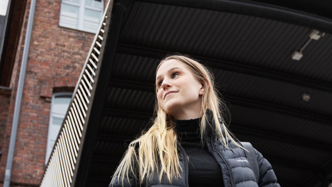 Johanna Sirviö kävelemässä ulkona. Taustalla näkyvä korkea rakennus on Solo Sokos Hotel Torni Tampere.