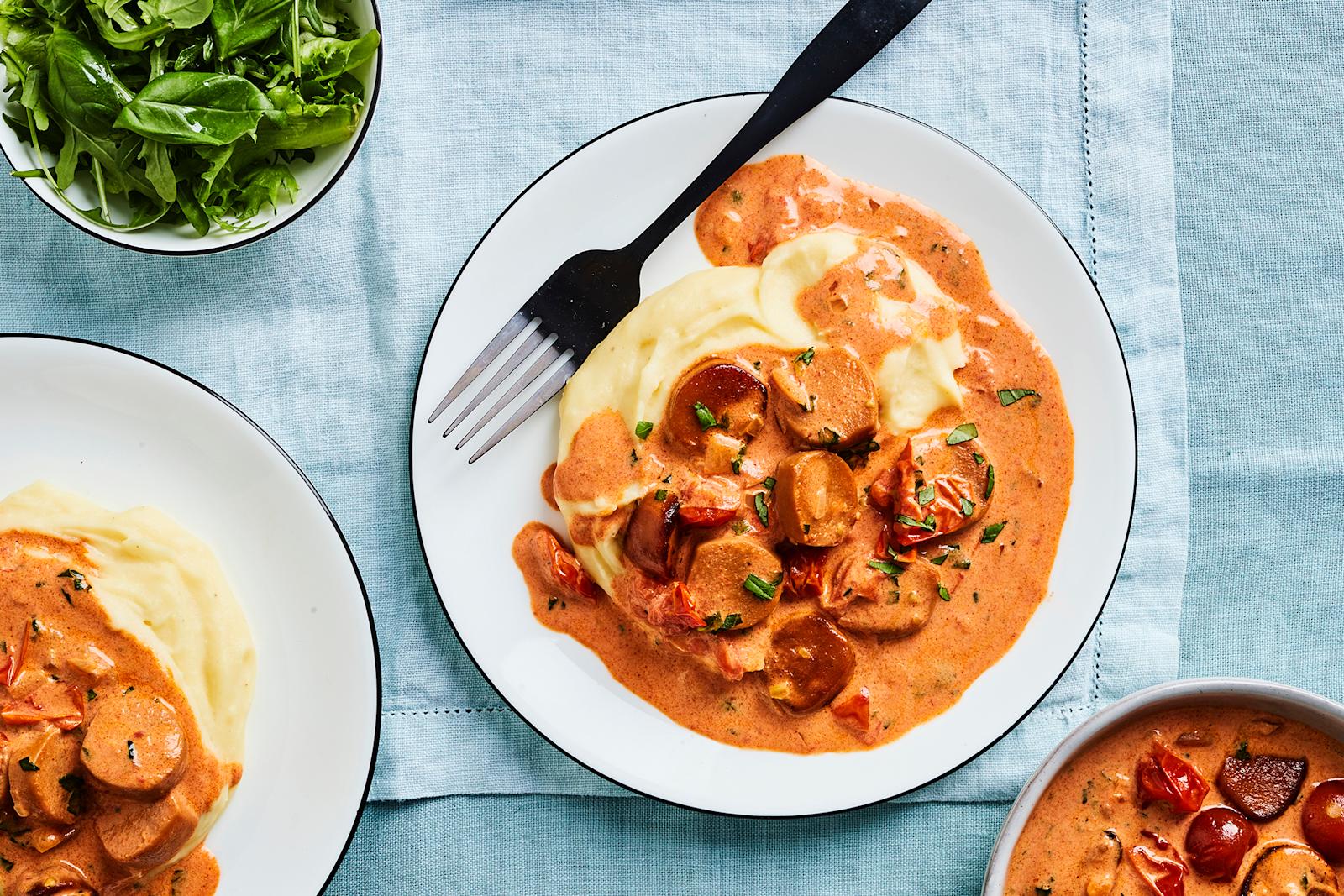 Kahdella lautasella vegaanista makkarakastiketta ja perunamuusia.