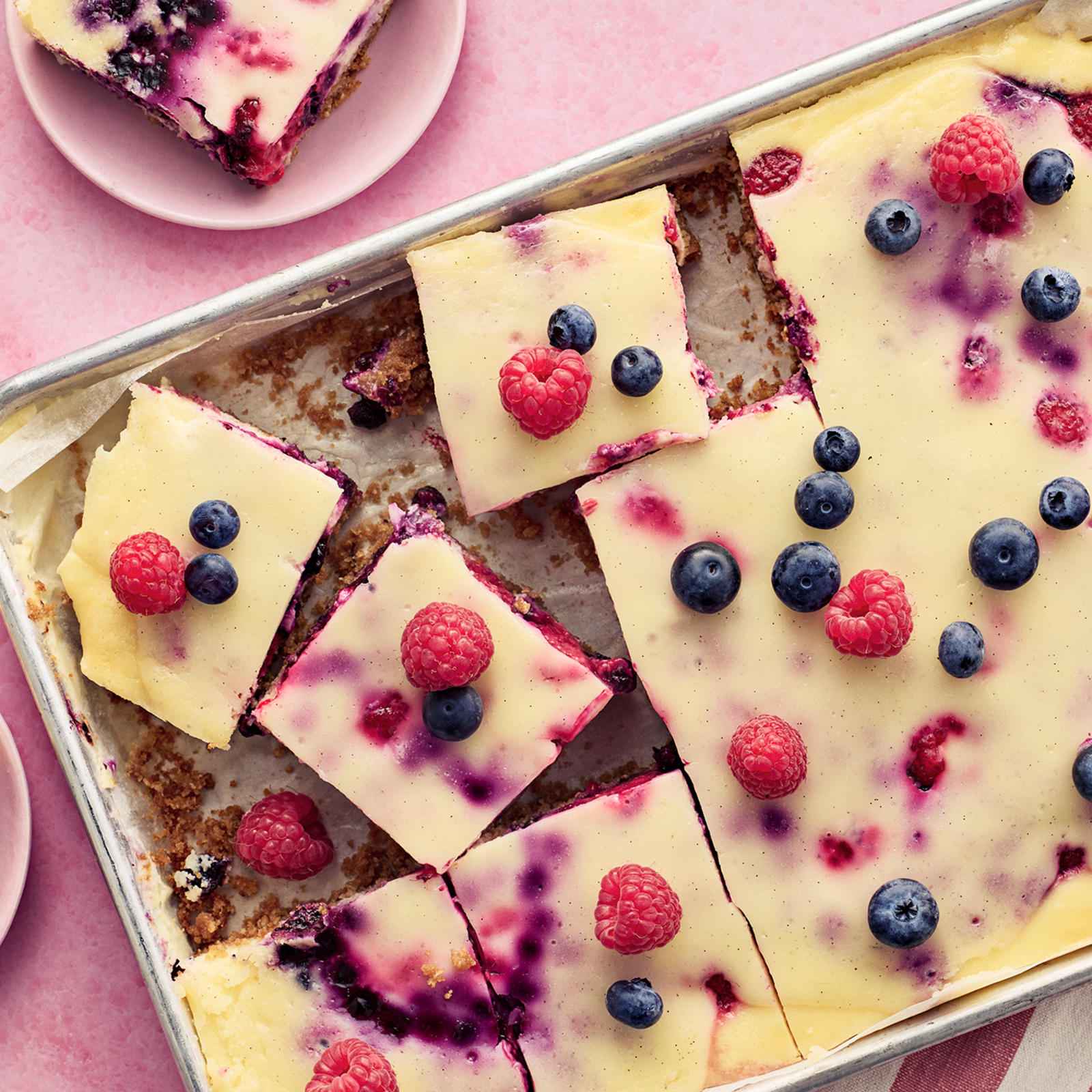 Marjainen juustokakku vuoassa ja paloja lautasilla