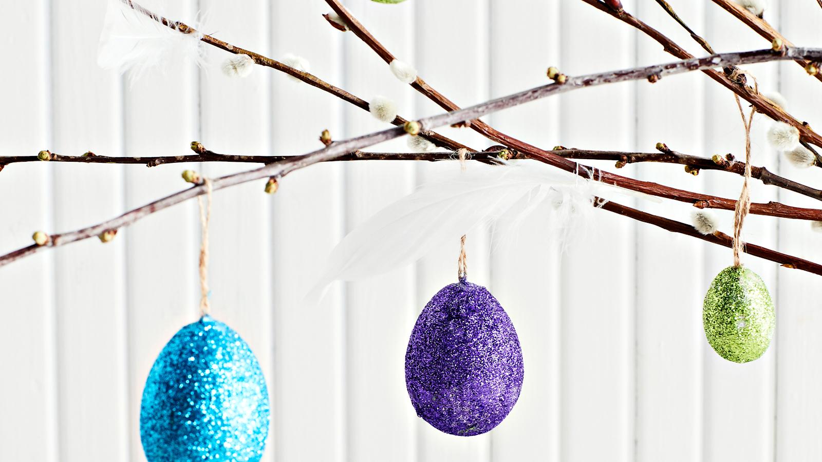 Kimallejauheella koristeltuja pääsiäismunia pajunoksiin ripustettuina.