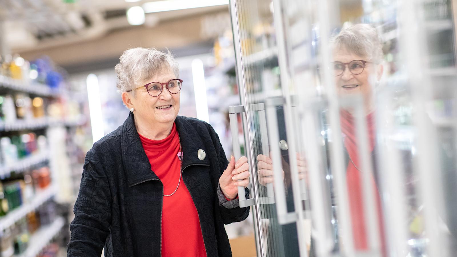 Eeva-Liisa Isomäki seisoo kaupassa ja pitelee kiinni ovenkahvasta.