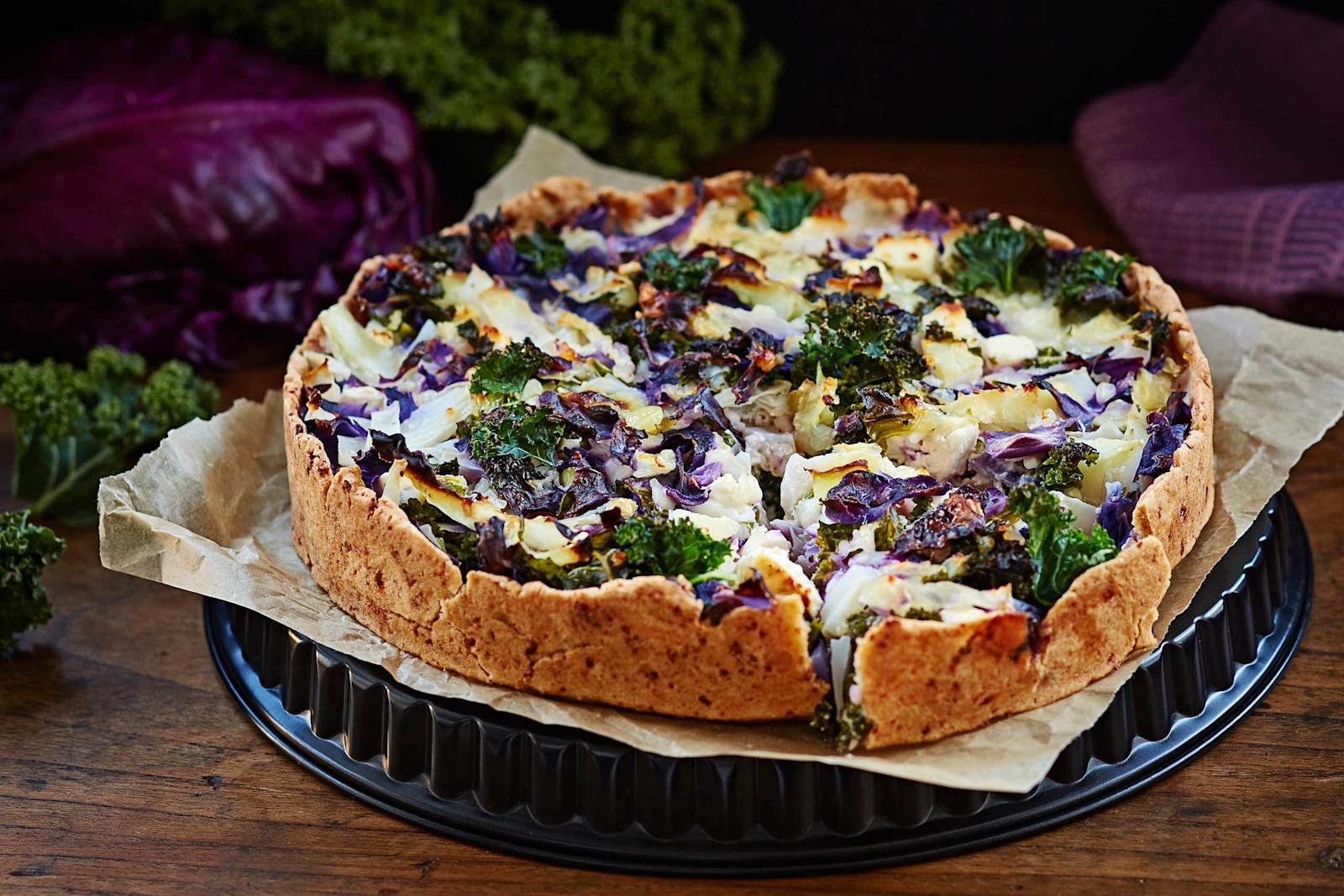Pöydällä piirakkavuoan päällä kokonainen kaalipiirakka.