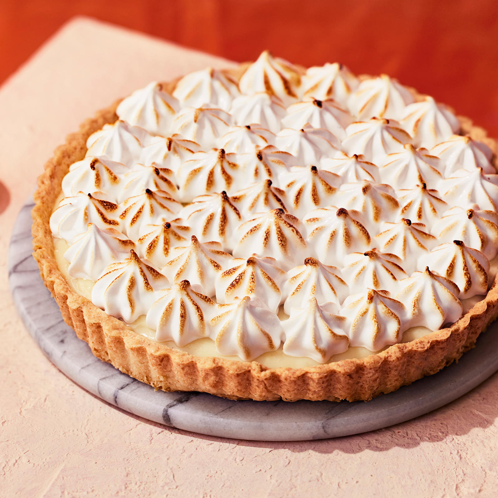 Vegaaninen sitruunamarenkipiirakka, jonka vieressä puolitettu sitruuna