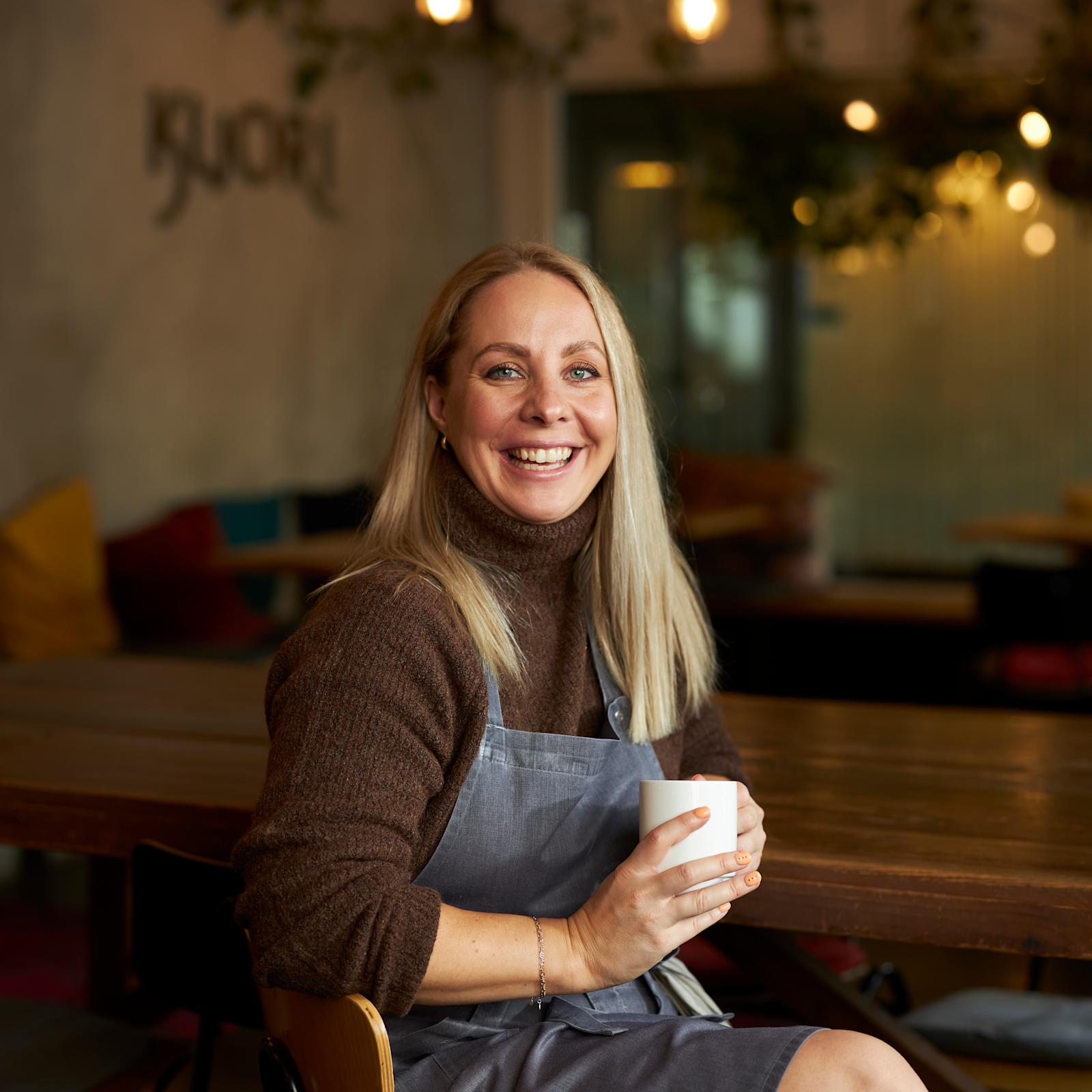 Katariina Vesterinen pitää käsissään kahvikuppia ja hymyilee