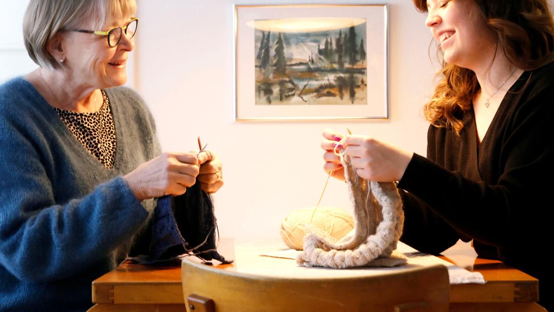 Michelle Ålander ja hänen mummonsa Kaarina Lindqvist neulovat pöydän ääressä.