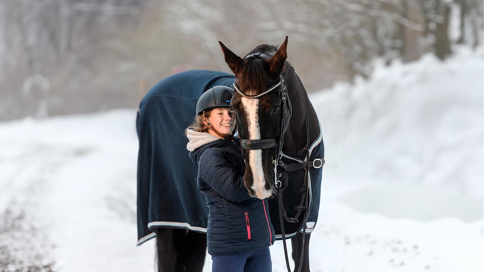 Pararatsastaja Jessica Kerttunen hymyilevänä Danny-hevosensa vierellä.