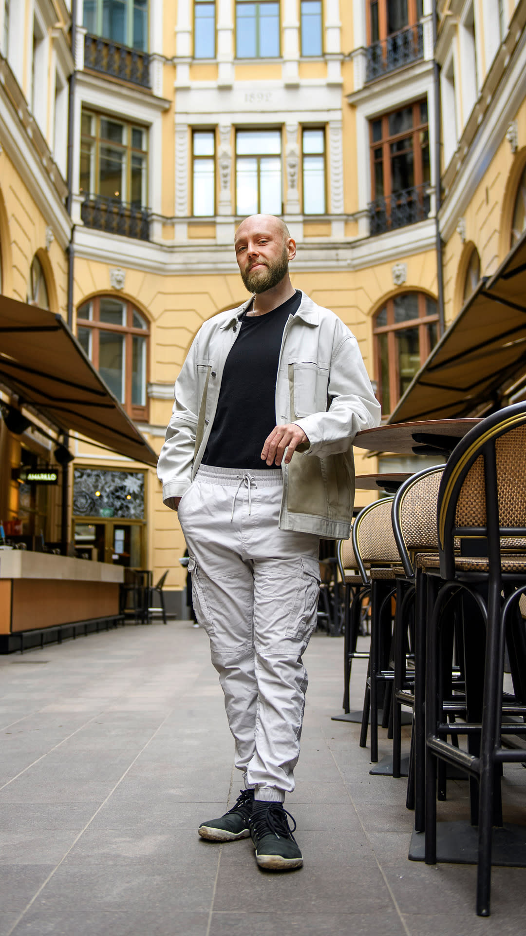Valkoisiin pukeutunut mies seisoo sisäpihalla.