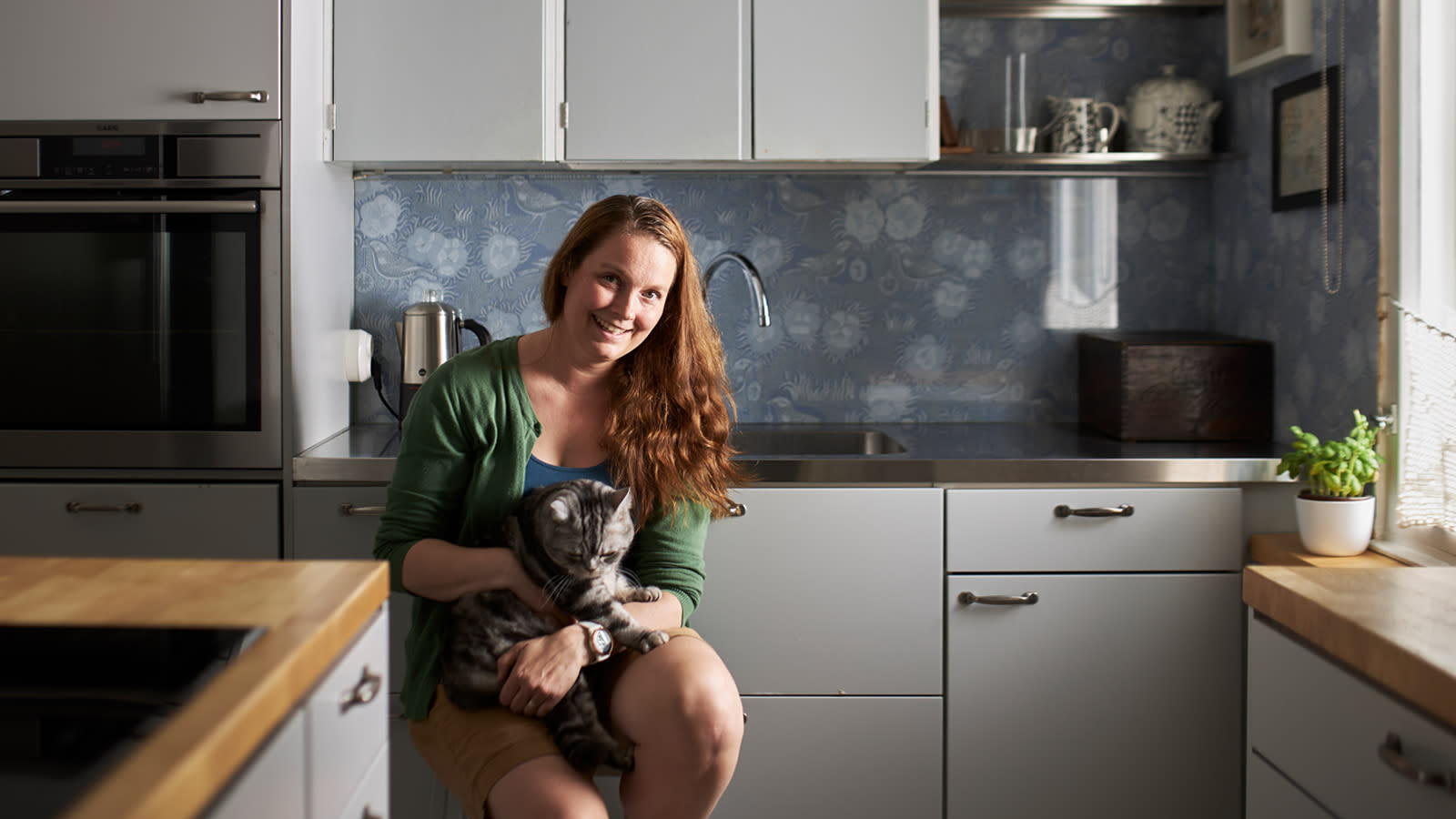 Elina Kyytsönen istuu tuolilla keittiössä kissa sylissään.