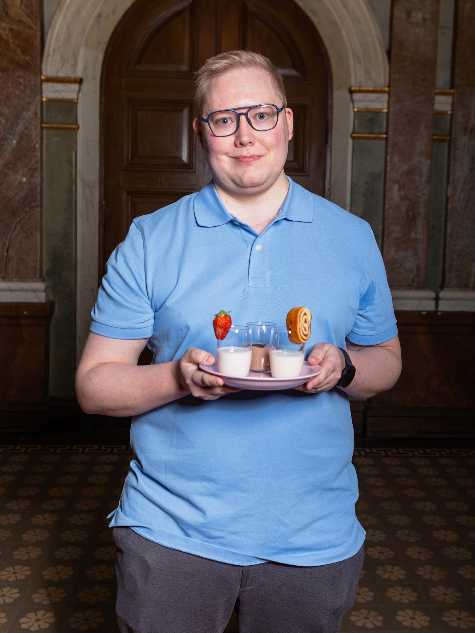 Teemu Koitto pitelee käsissään kolmea lasia herkkupirtelöä. Hänellä on päällään sininen pikeepaita.