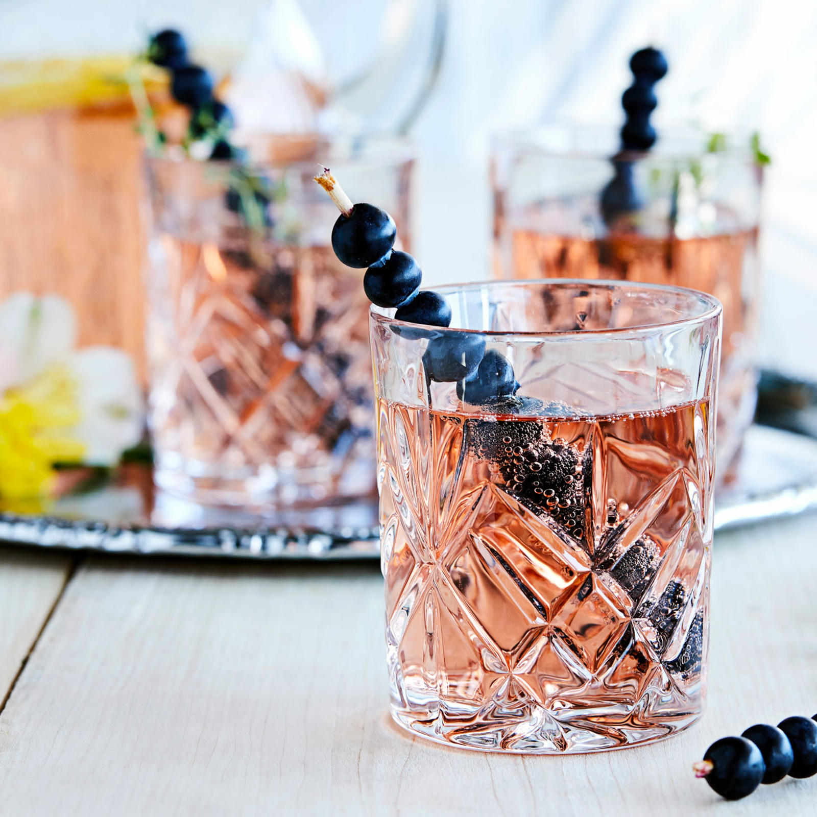 Pensasmustikoilla koristeltu drinkkitikku kruunaa kesän juhlajuomat.