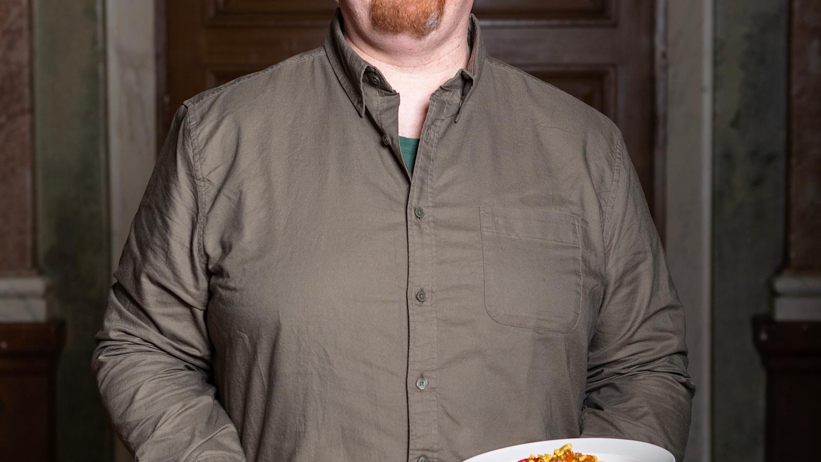 Lauri Hakala pitelee kolmea syvää lautasta, jotka sisältävät kolmea eri ruokaa. Laurilla on päällään kauluspaita.