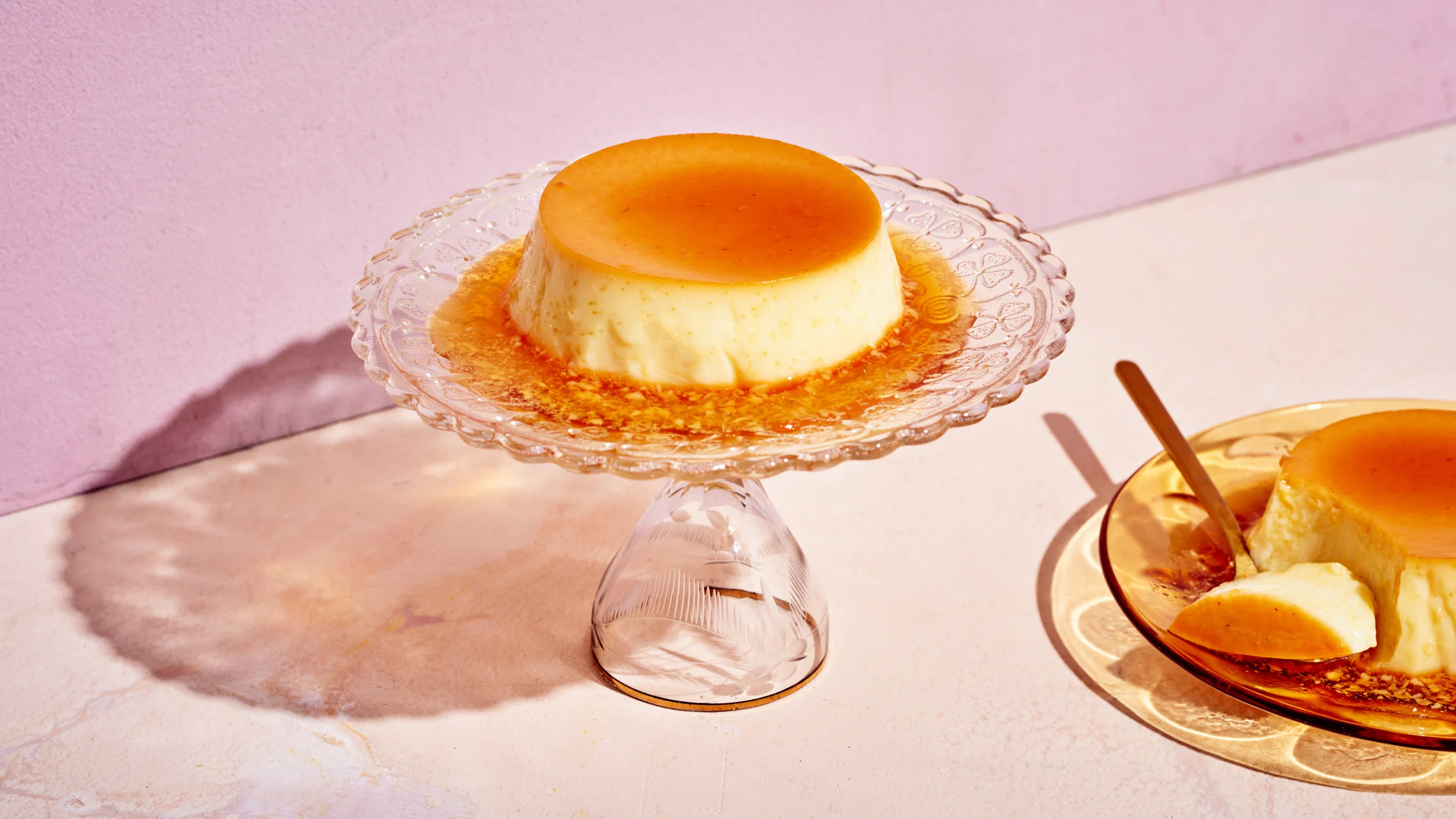 Paahtovanukas jalallisella tarjoiluastialla. Vieressä lautasella toinen paahtovanukas, josta on lohkaistu pala lusikalla.