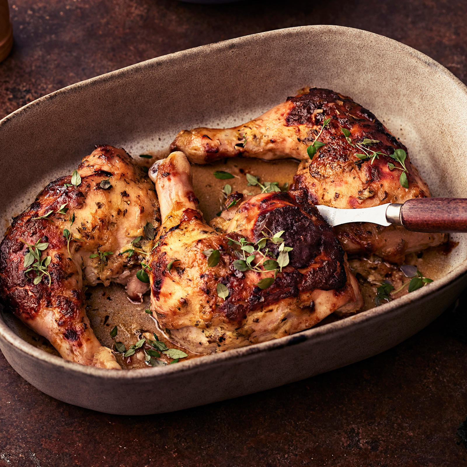 Sinappikana timjamilla koristeltuna uunivuoassa, jossa tarjoiluotin. Vuoan vieressä leipää, salaattikulho ja pippurimyllyjä.