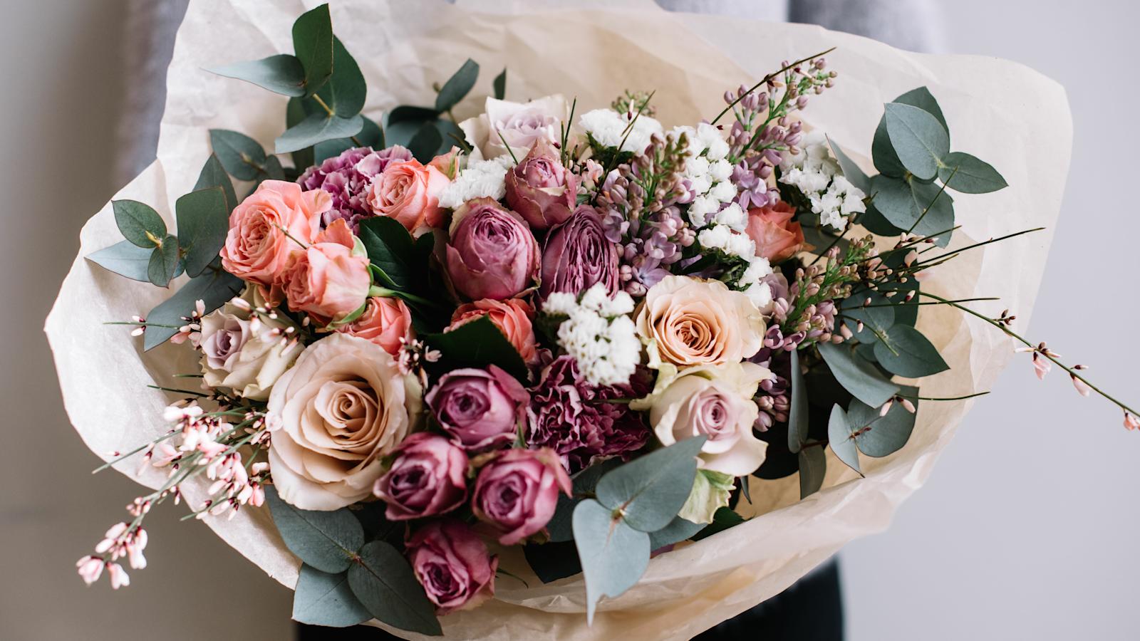 Nainen pitää käsissään suurta kukkakimppua