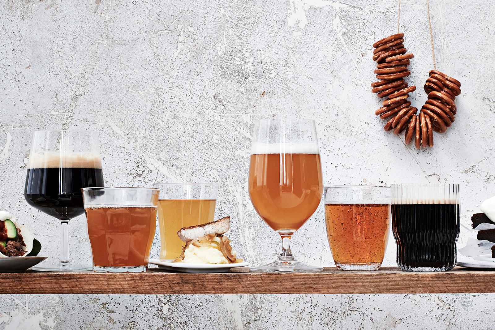 Kuusi erilaista olutta laseissa sekä oluisiin sopivia ruokia.