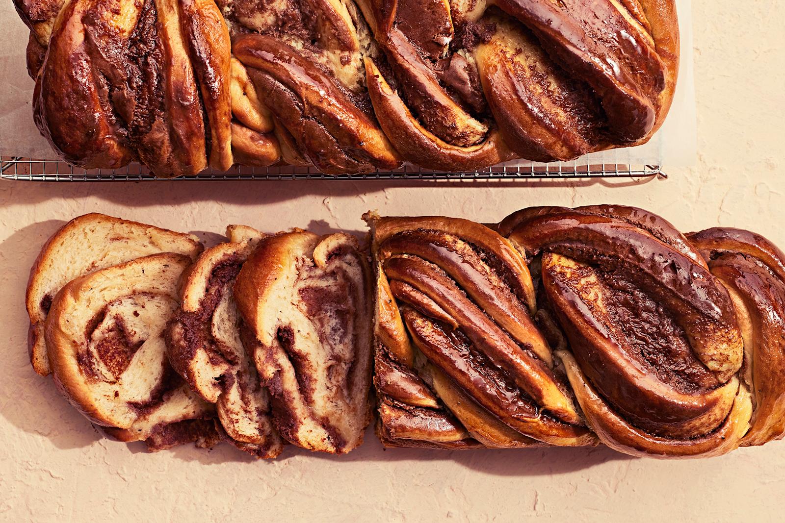 Suklainen pullapitko, josta leikattu neljä viipaletta. Vieressä kokonainen pitko leivinpaperoidun ritilän päällä.