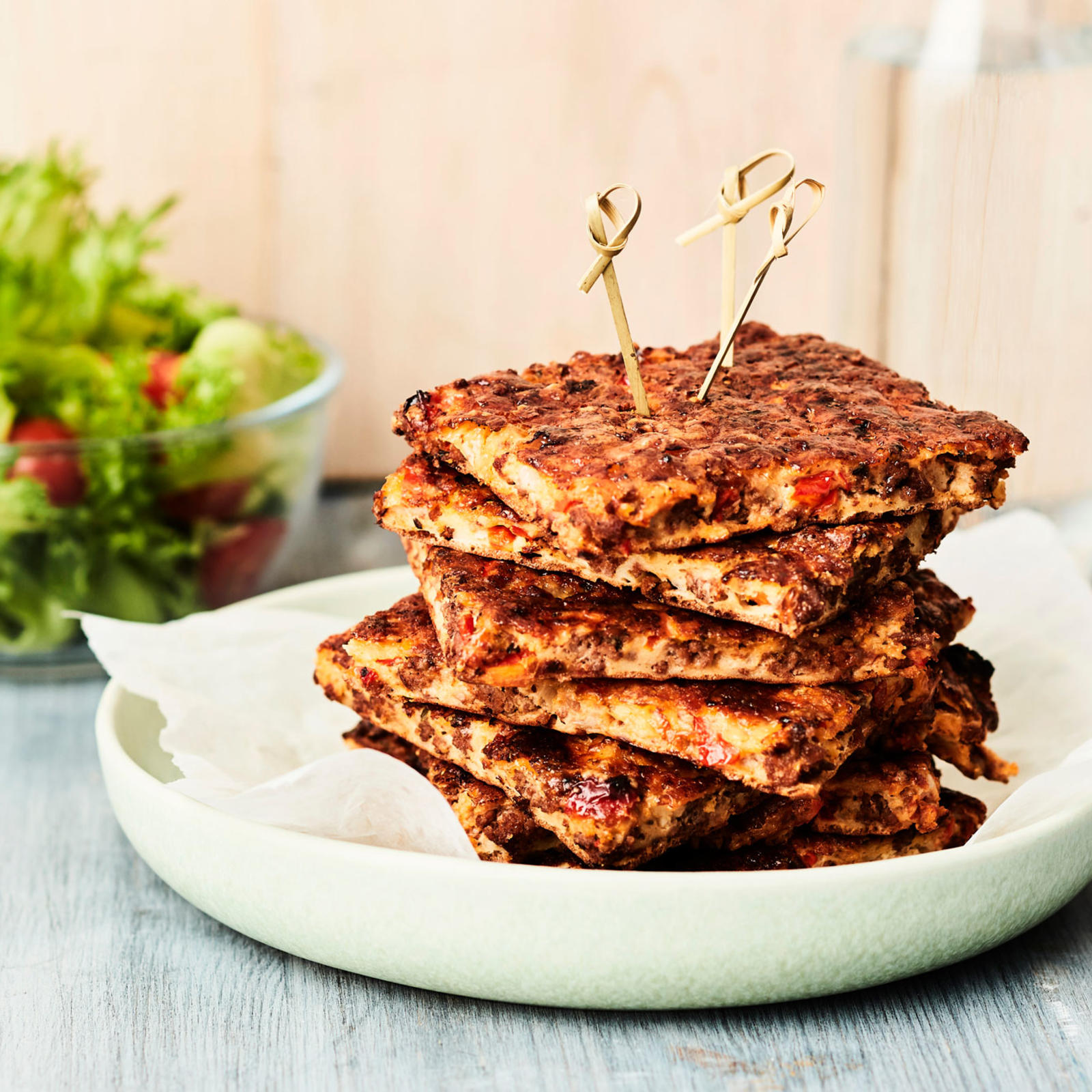 Helppo jauhelihapannari paloiksi leikattuna lautasella. Taustalla kulho vihersalaattia ja vesikannu.