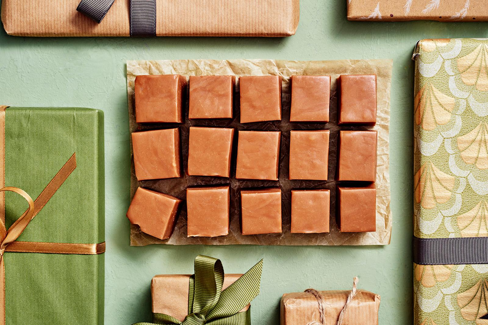 Maitosuklaafudge leikattu palasiksi. Ympärillä joululahjapaketteja.