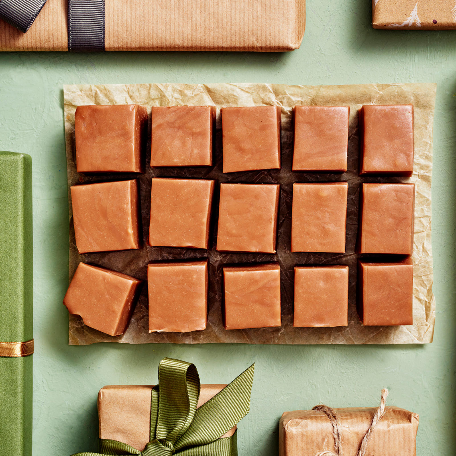 Maitosuklaafudge leikattu palasiksi. Ympärillä joululahjapaketteja.