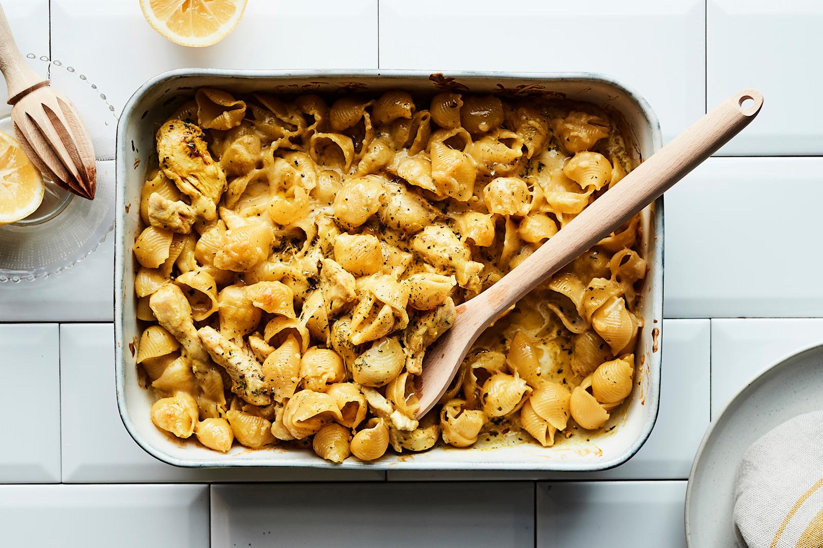 Uunivuoka, jossa Palermon kanapastaa sekä puinen otin. Vieressä puinen sitruspuserrin ja puolikas sitruuna lasilautasella, sekä valkoinen ruokalautanen ja lautasliinan kulma.