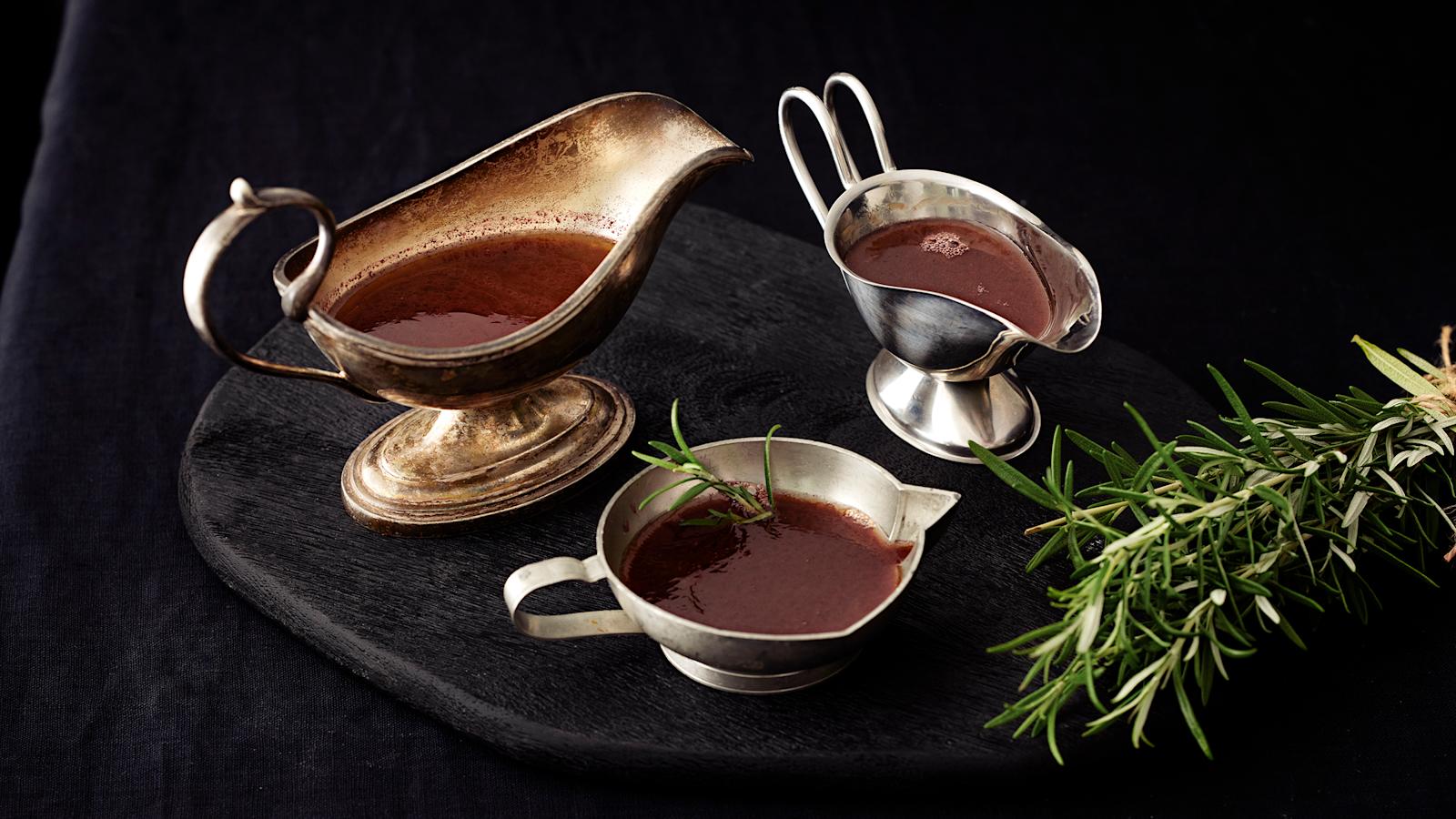 Rosmariini-punaviinikastiketta kolmessa kastikekannussa. Kannujen vieressä rosmariinin oksa.