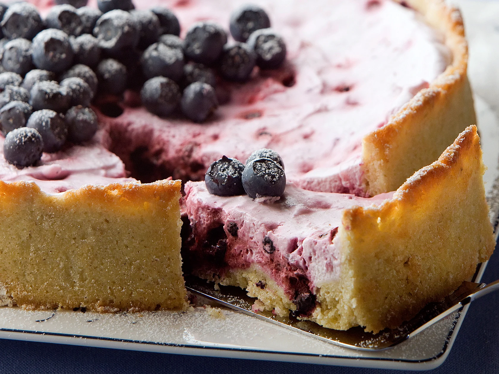 Mustikka-rahkatorttu, josta leikattu pala kakkulapion päälle.