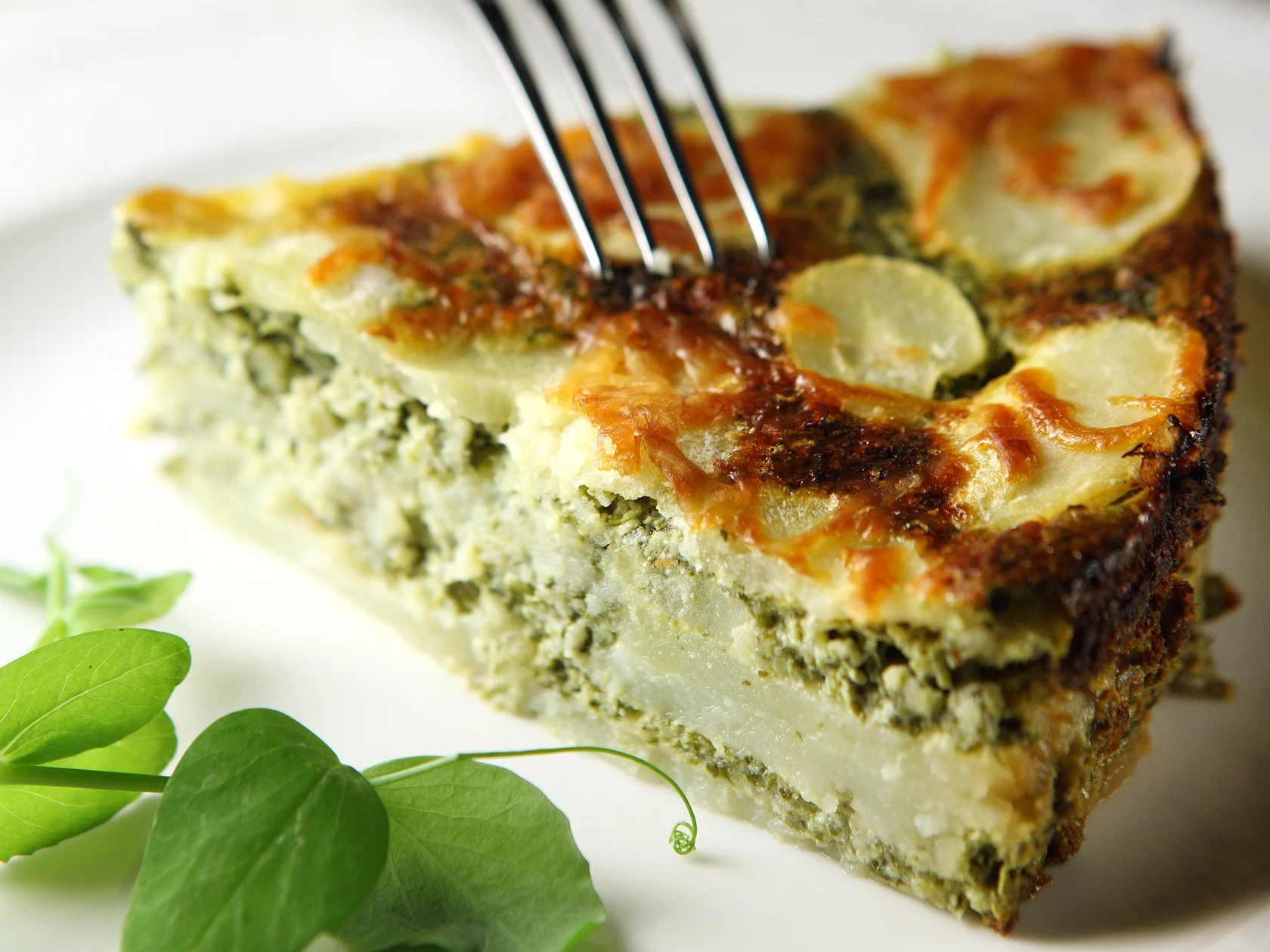 Pala peruna-pinaattigratiinia lautasella.