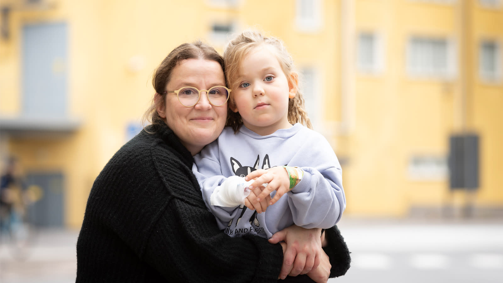 Maria Tiira istuu Alma-tytön kanssa pihalla.