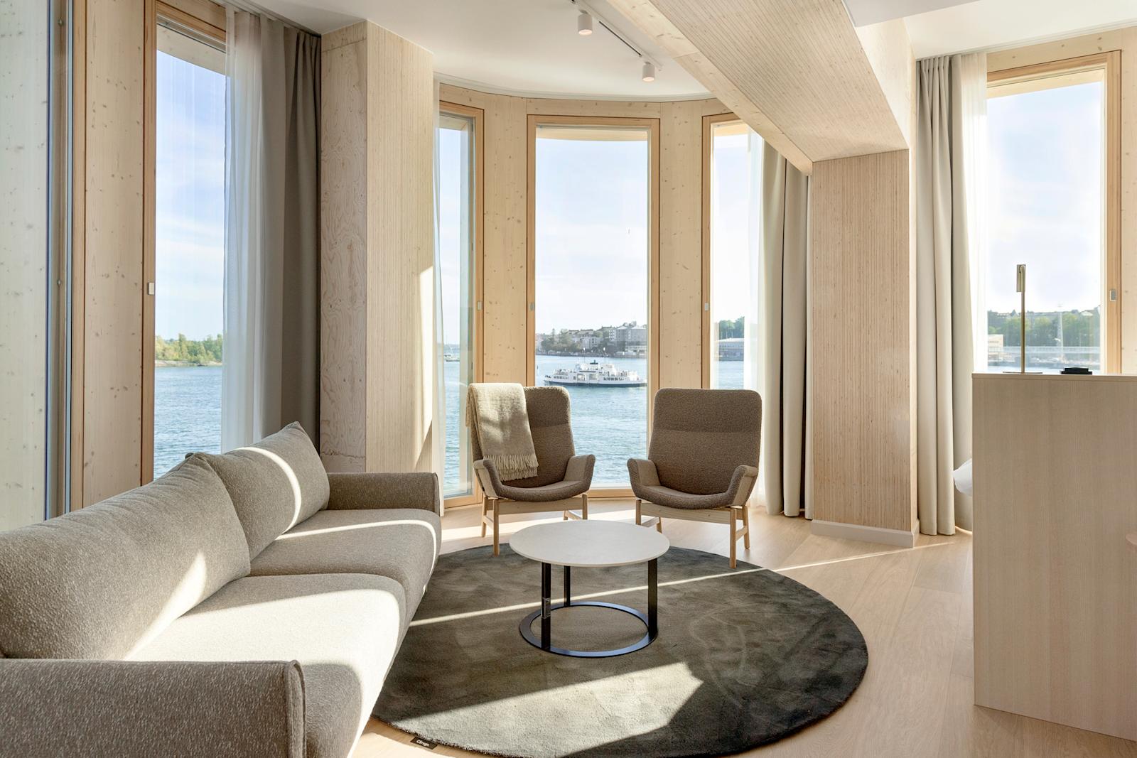 Solo Sokos Hotel Pier 4 -hotellin tila, jossa nojatuoleja ja useita suuria ikkunoita, joista näkyy merimaisema