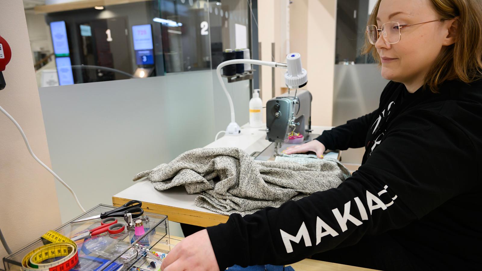 Anita Wallin pöydän ääressä muokkaamassa paitaa