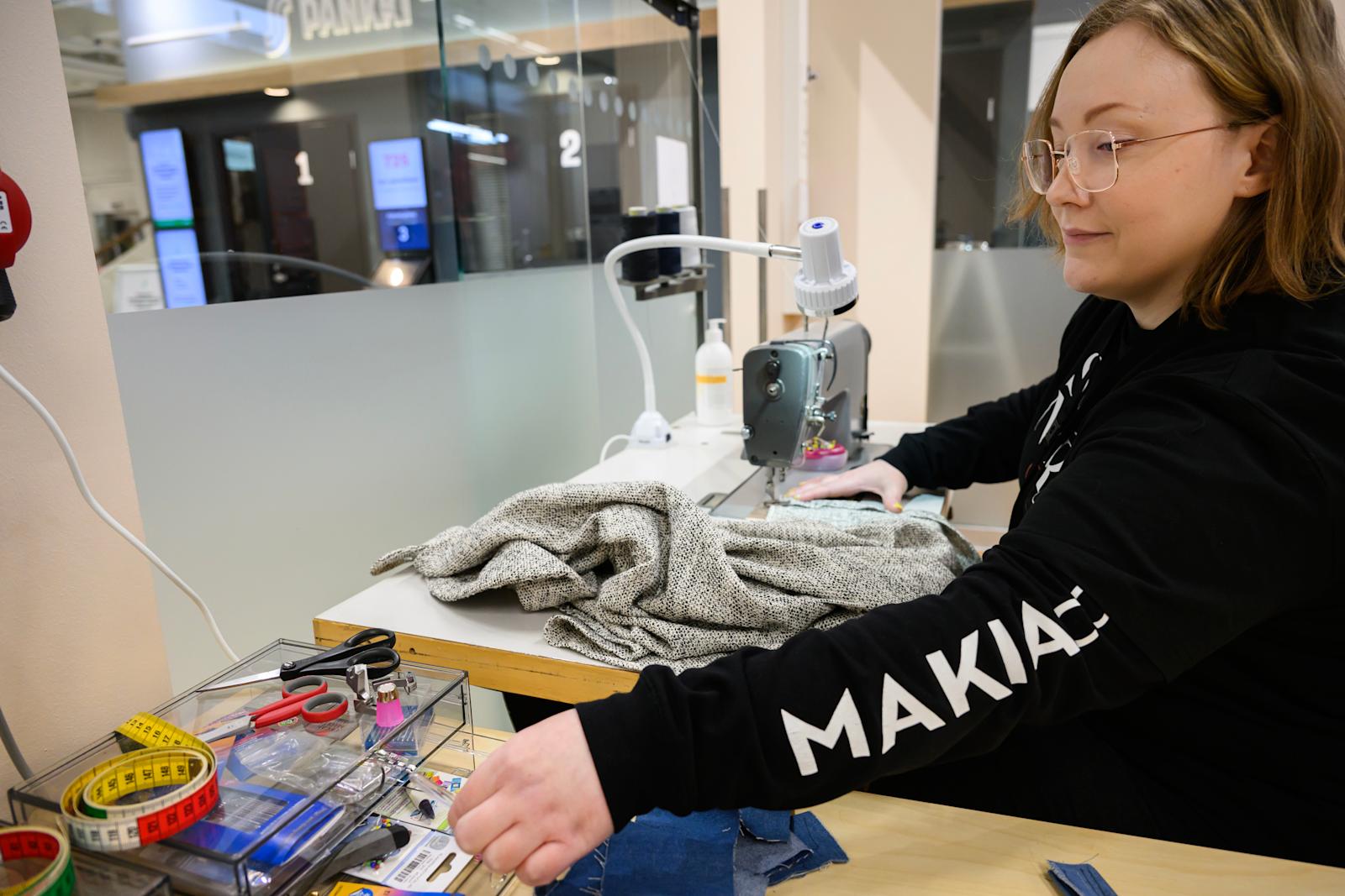 Anita Wallin pöydän ääressä muokkaamassa paitaa