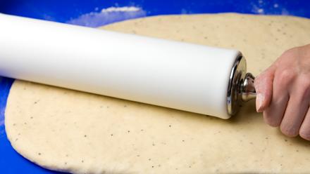 Kumoa kohonnut taikina jauhotetulle leivonta-alustalle. Vaivaa taikinasta ilmakuplat pois. Kauli taikina jauhojen avulla laajemmaksi, suorakaiteen muotoiseksi levyksi (n. 30 x 40 cm).